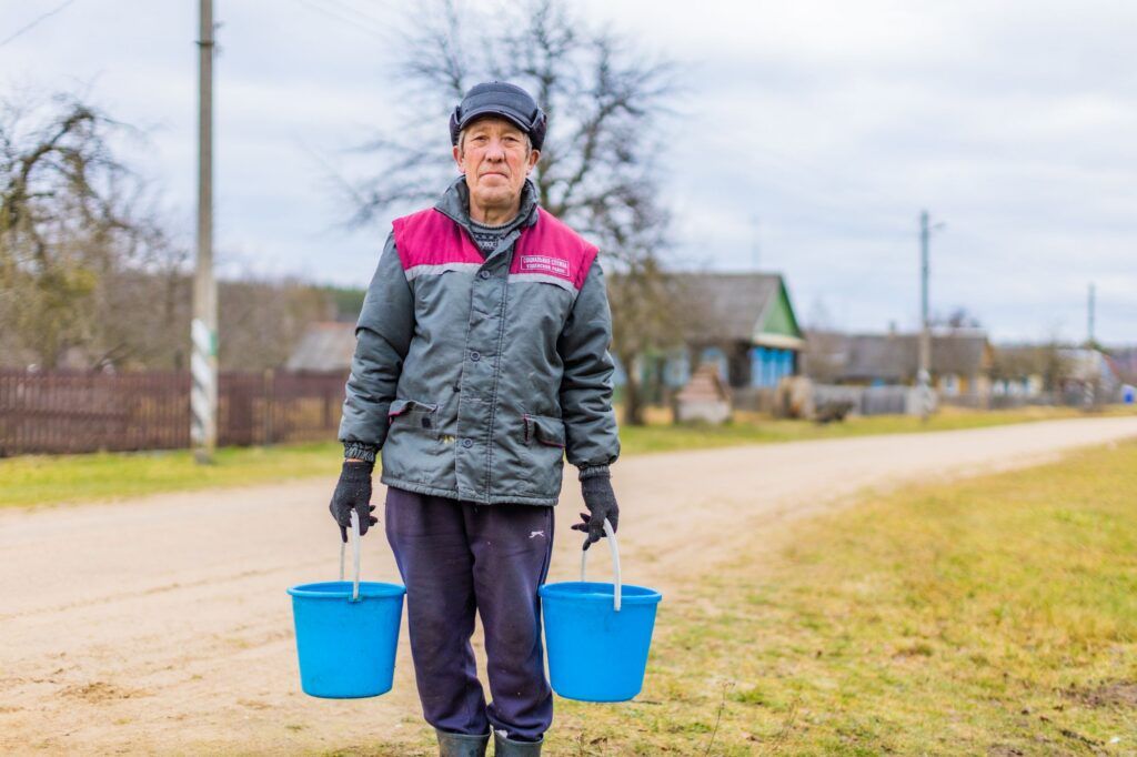 мужчина несет ведра с водой